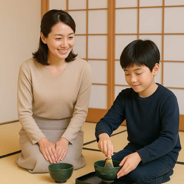 母親が隣で微笑みながら見守る中、息子が茶筅で抹茶を点てている写真。