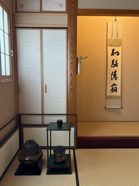 掛け軸『和敬清寂』が掛けられた床の間と、釜や棚が置かれた茶室の様子。