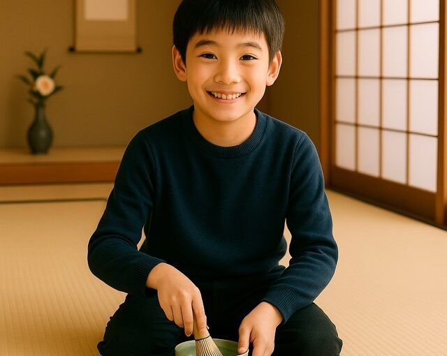 畳の茶室で紺色のセーターを着た小学生の男の子が正座しながら笑顔でお茶を点てている。親子で楽しめる茶道体験の様子（茶道教室結空・新宿区戸山）。